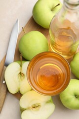 Fresh cider in glass, bottle, apples and knife on beige table, top view