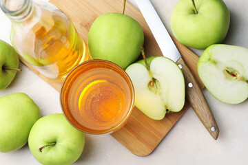 Fresh cider in glass, bottle, apples and knife on beige table, flat lay