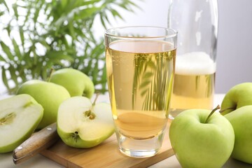 Fresh cider in glass, bottle, apples and knife on table, closeup