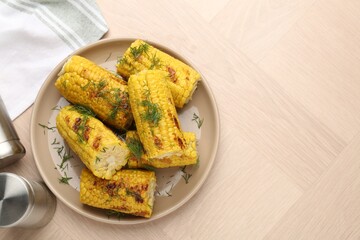 Pieces of tasty grilled corncobs with dill on wooden table, top view. Space for text