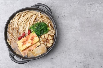 Tasty ramen with enoki and king oyster (eryngii) mushrooms on light grey table, top view. Space for text