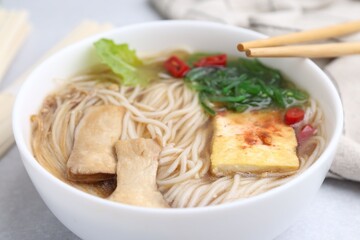 Tasty ramen with enoki and king oyster (eryngii) mushrooms on white table, closeup