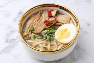 Tasty ramen with enoki and king oyster (eryngii) mushrooms on white marble table, closeup
