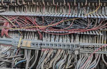 Close-up of tangled electrical wiring and terminal blocks inside an industrial control panel with...