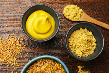 Different types of mustard on wooden table, flat lay