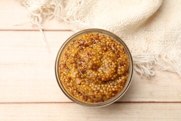 Whole grain mustard in glass bowl on wooden table, top view