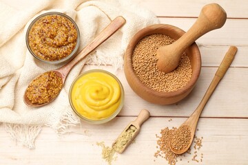Different types of mustard on wooden table, flat lay