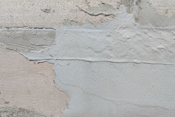 Close-up texture of a rough concrete wall with old plaster, cracks, and peeling surface, showing weathered construction material detail for background or design use
