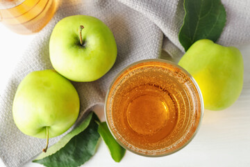 Fresh cider in glass and apples on white table, flat lay