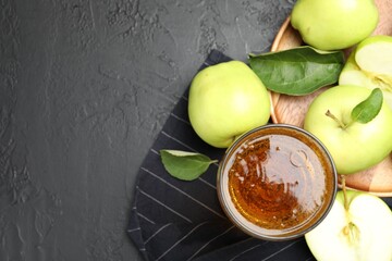 Fresh cider in glass and apples on black table, flat lay. Space for text