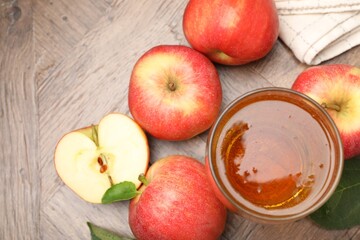Fresh cider in glass and apples on wooden table, flat lay