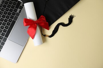Graduation cap, laptop and diploma on beige background, flat lay. Space for text