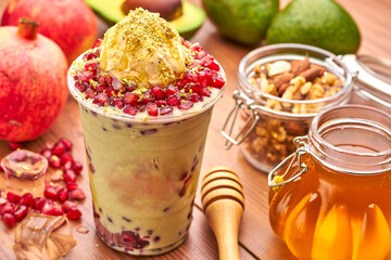 Creamy Avocado Smoothie with Pomegranate, Nuts, Honey, and a scoop of ice cream in plastic cup side...