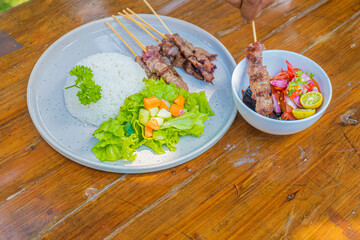 Delicious grilled satay skewers with rice and fresh salad, perfect for a healthy lunch