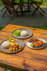 Delicious Indonesian cuisine featuring satay, rice, and fresh salads on a rustic wooden table setting