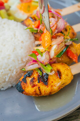 Delicious grilled chicken satay skewers with vibrant fresh vegetable salad and rice on a plate