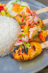 Delicious grilled chicken skewers with rice and vibrant toppings, a culinary delight!