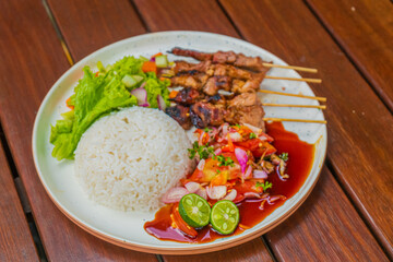 Delicious grilled meat skewers with rice and fresh salad on a plate, ready to eat