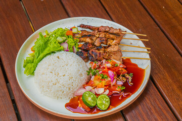 Delicious grilled skewers with rice and fresh salad on a plate, ready to eat and enjoy