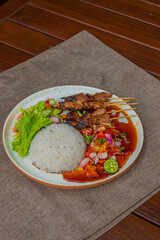 Delicious Indonesian satay meal with rice and fresh vegetables on a beautifully plated dish