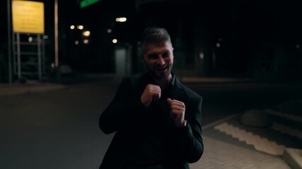 Cheerful Businessman in Suit Dancing Happily on Street at Night