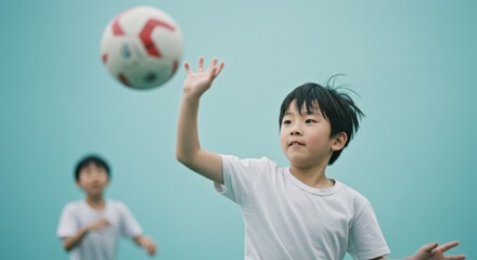 Young boy playing soccer and reaching for ball on blue background
