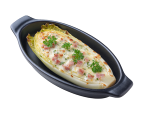 A single endive braised and baked with cheese and bacon, garnished with parsley, served in a black oval gratin dish isolated on transparent background