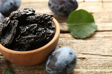 Dried prunes and fresh plums on wooden table, closeup. Space for text