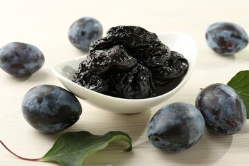 Dried prunes and fresh plums on wooden table, closeup