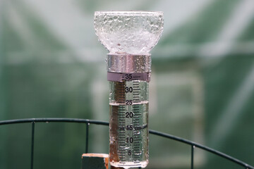 Filled rain gauge in a soaking wet rainy garden