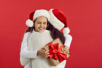Happy family in red santa hats cuddling in celebration of Christmas Holiday. Happy joyful teen girl...