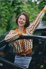 Car, driver, woman, smile a cheerful woman stands beside a car with arms raised, joyful energy and...