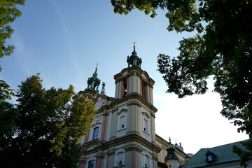 Obraz premium Historic church facade with towers and green domes framed by leafy trees, blending cultural heritage, timeless faith, and architectural elegance
