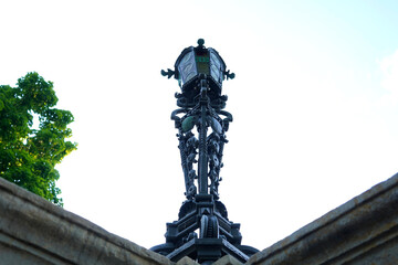 Ornate wrought iron lantern rises above stone structure, symbolizing vintage craftsmanship, decorative urban detail, and timeless architectural charm