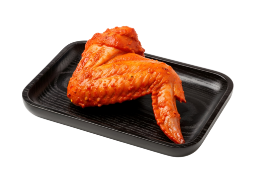 A seasoned chicken wing rests on a dark wooden platter against a black background.