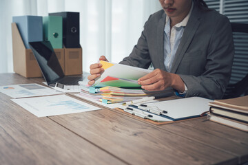 Businessman working through pile of documents to find unfinished documents, information on pile of...