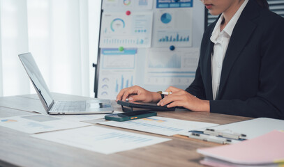 Professional Analyzing Data: A business professional diligently analyzes complex data on a laptop, surrounded by charts and documents, representing focused work and analytics.