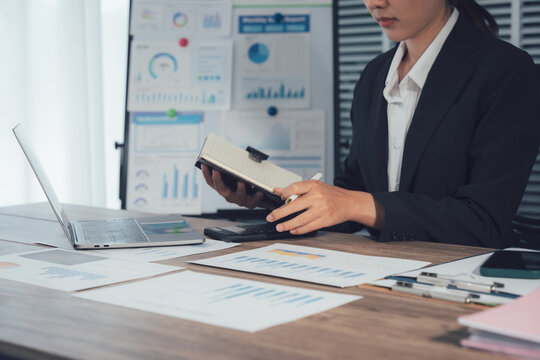 Strategic Assessment: A focused business person meticulously reviews financial reports amidst charts, a calculator, and a laptop, engaging in a precise analysis.