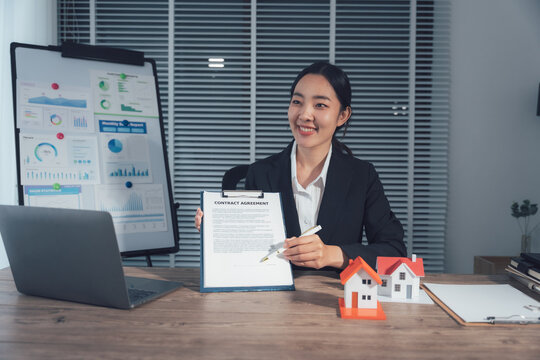 Business Woman Presenting: A professional woman in a sleek suit presents a contract agreement with a smile. Behind her, a presentation board showcases financial data.