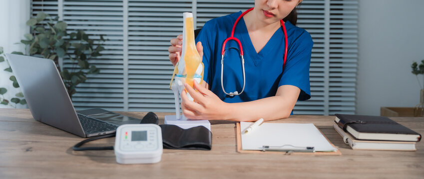 Medical Professional Explaining Knee Model: A focused medical expert provides insight, displaying a detailed model of the knee joint with clarity and precision, promoting healthcare education.