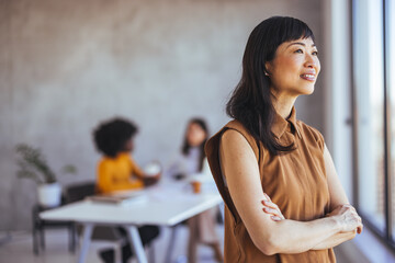 Confident Businesswoman Standing Calmly in Modern Office Space with Colleagues Nearby