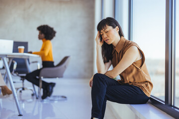 Worried Businesswoman Sitting Near Window in Modern Office Environment