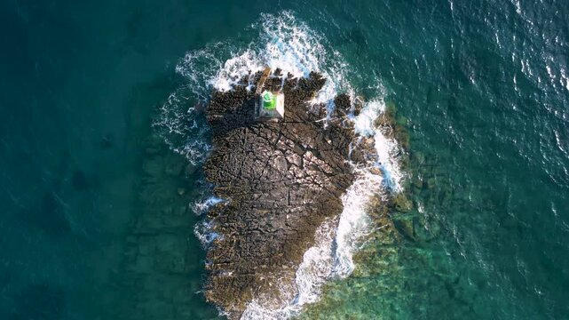 Top down view of Punta Planka green lighthouse on the sharp rocks submerged in turquoise adriatic sea near town of Rogoznica, Croatia