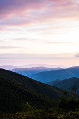 Fototapeta premium Sunset In The Mountains With Silhouettes Of Peaks In The Rays Of The Setting Sun, Scenic Mountain Landscape In Yellow Red And Pink Hues, Evening Nature Background