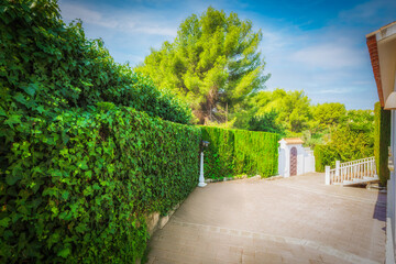 A garden fence with a lantern, a monumental gate, and a blue sky.