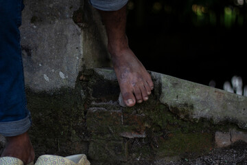 Barefoot person stepping on a mossy stone ledge near water