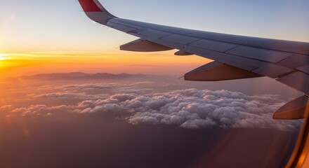Obraz premium Airplane Wing Over Clouds at Sunset