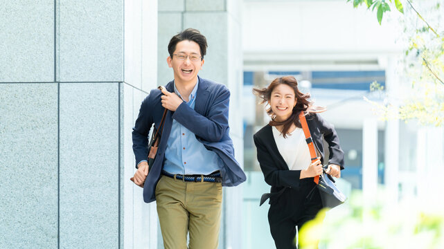 オフィス街を走る男女2人のビジネスマン