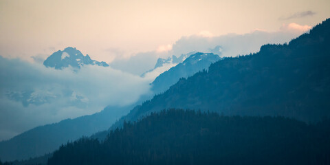Looking across the layers of forest and mountains in the clouds at sunset near Whistler, Canada