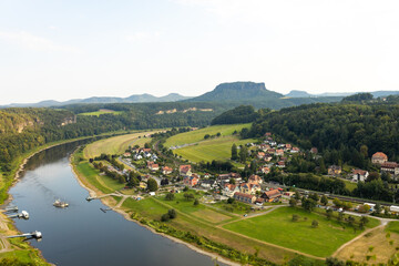 Naklejka premium Panoramic aerial view of Saxon Switzerland National Park, Germany. Elbe river winding through green valley with a small village and Lilienstein mountain on the horizon. Scenic summer landscape in Saxo